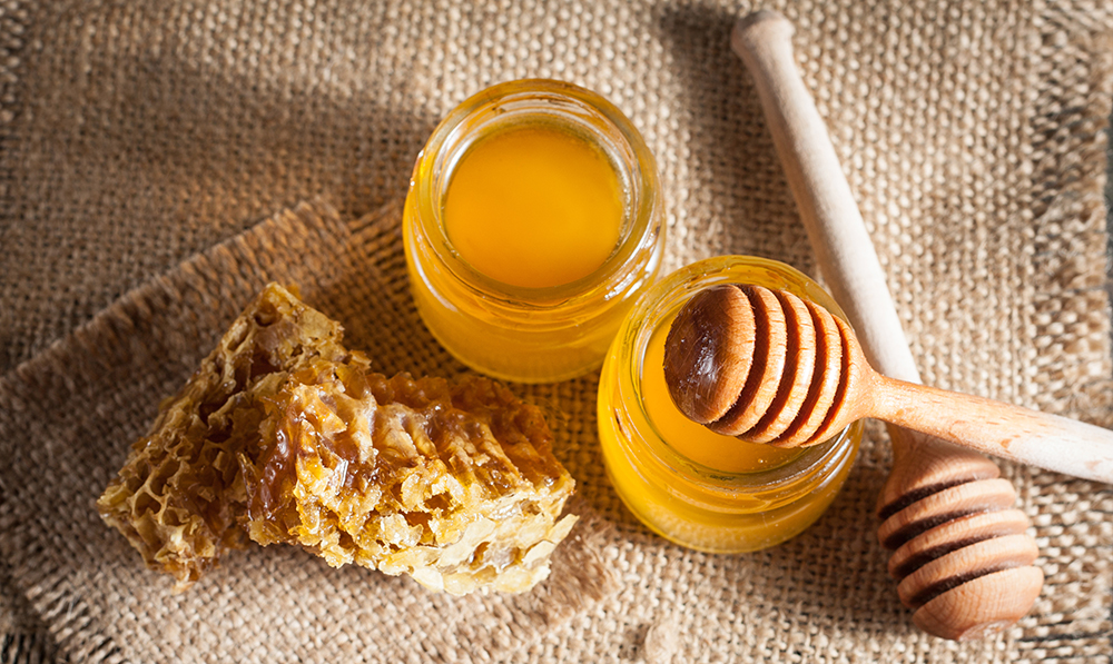 Honey in jars with honeycomb on burlap placemat