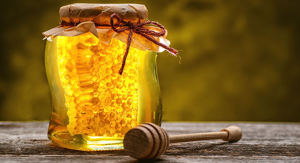  Jar of honey on table top with honey dipper