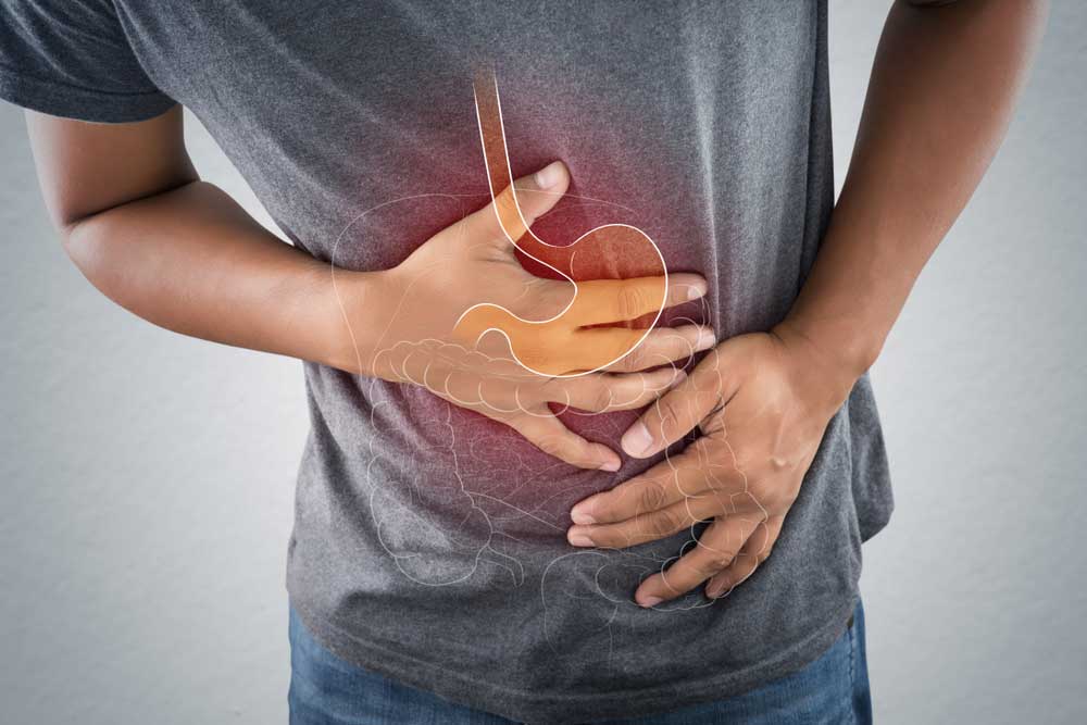 Man bent over holding stomach with drawing of stomach overlay